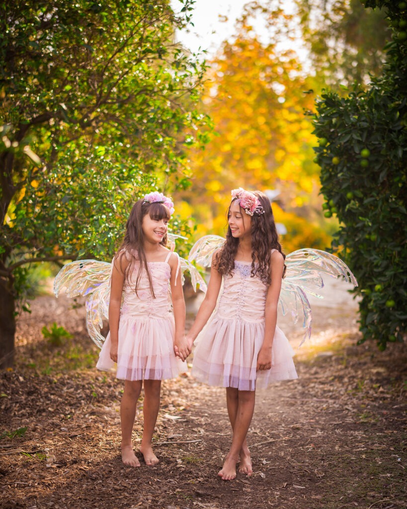 Girls sisters fairies wings tutus dresses barefoot outside California