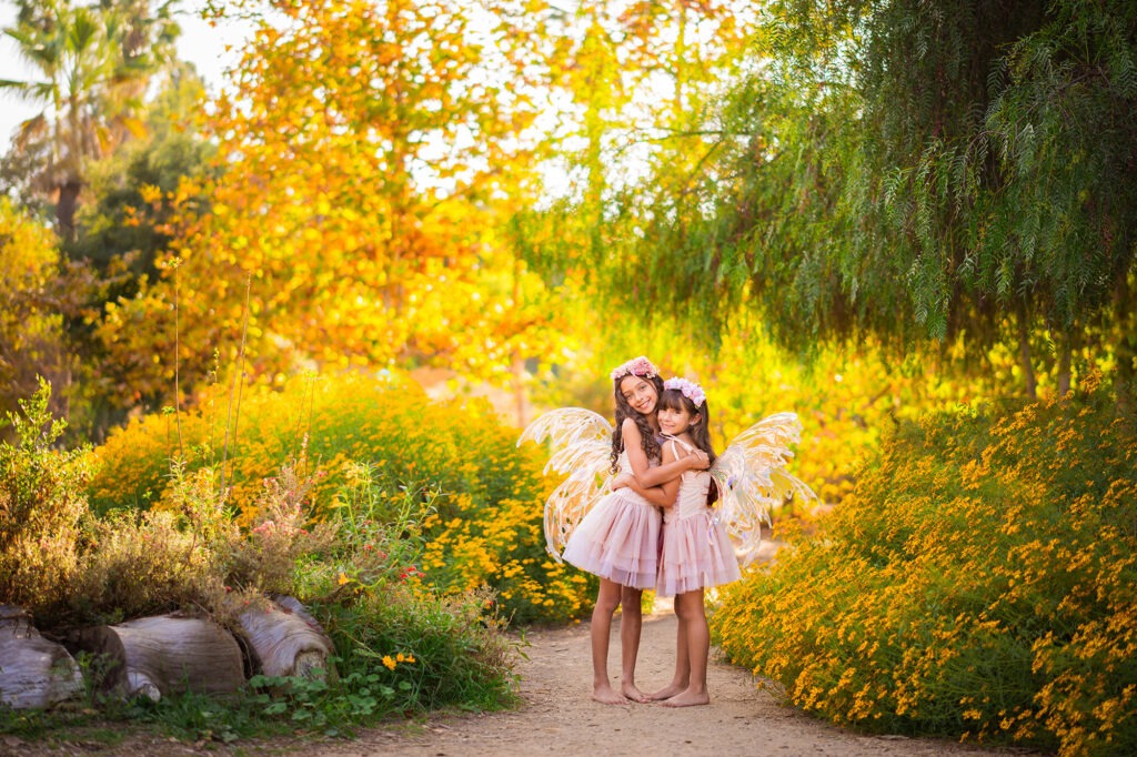 Girls sisters hugging flowers outside California fairy