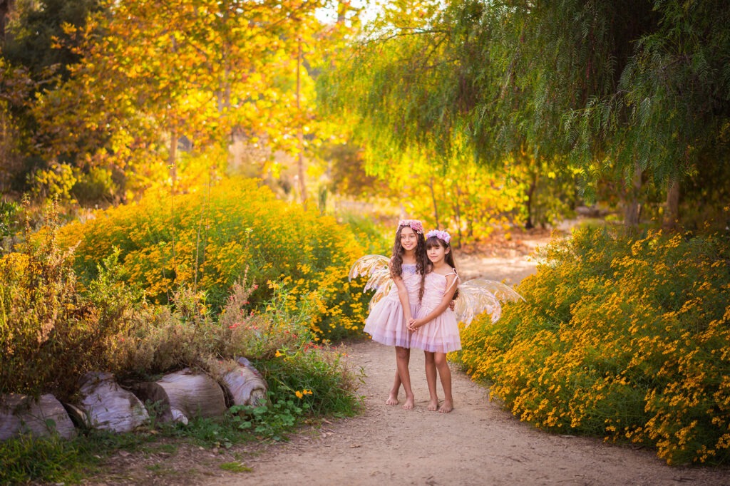 Girls sisters hugging flowers yellow outside California fairies