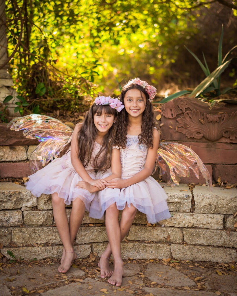 Girl sisters fairy wings dresses tutus outside California