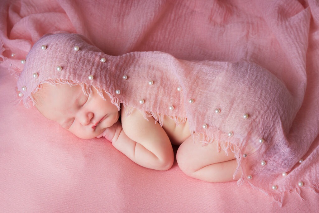 Newborn baby girl posed studio pink
