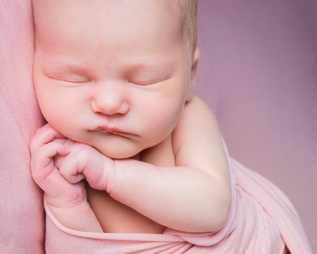 Baby girl newborn posed studio pink