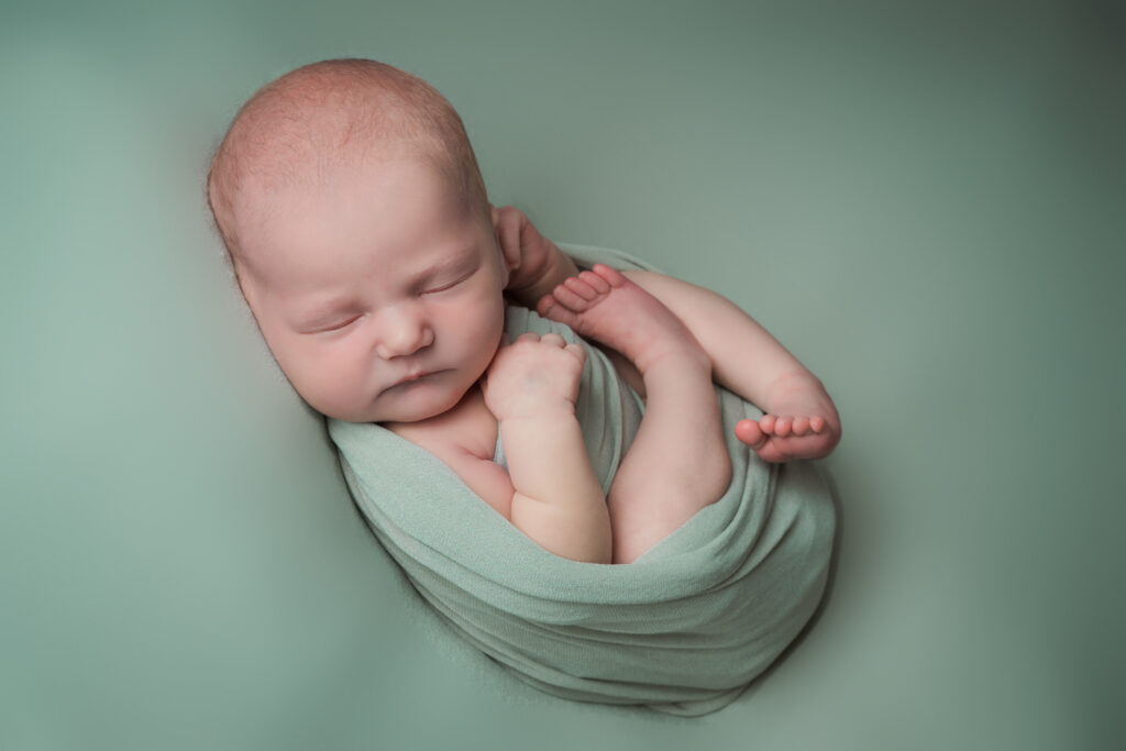 Newborn baby girl wrapped green posed