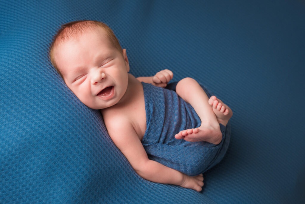 Newborn baby boy blue smile wrapped post studio
